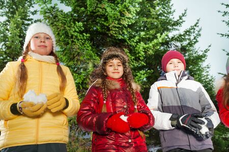 Boy and girls standing with snowballs in their hands preparing to play winter gamesの写真素材