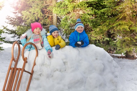Group of kids in snow fortress throw snowballs