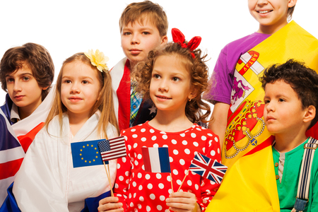 Portrait of six children wrapped in flags of USA and European nations holding pennons of EU, USA, France and UK, isolated on whiteの写真素材