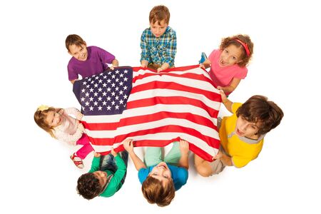 Top view of children standing in a circle around the flag of America, isolated on white backgroundの写真素材
