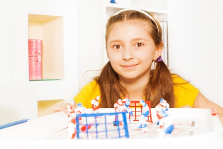Beautiful ten years old girl playing indoors ice hockey table board game