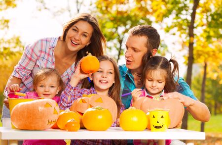 Happy family preparing Halloween pumpkins together with mom dad and three girlsの写真素材