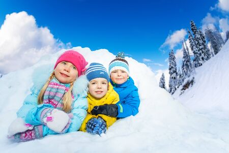 Group of kids crawl out of snow tunnel on sunny winter dayの写真素材