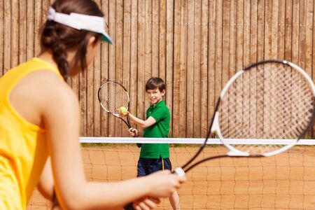 Sporty kid boy holding tennis ball and racket, starting set with his opponent on the clay courtの写真素材