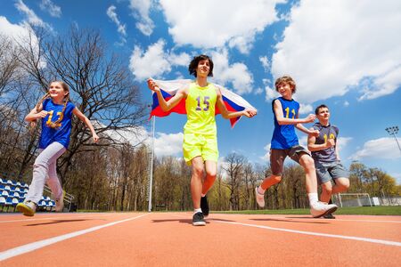 Happy teenage sprinters running with Russian flag in the stadium