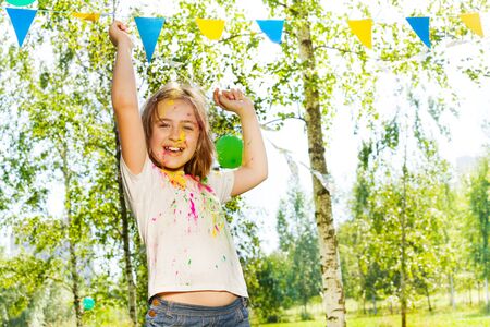 Happy little girl, smeared with colored powder, dancing on Holi color festivalの写真素材
