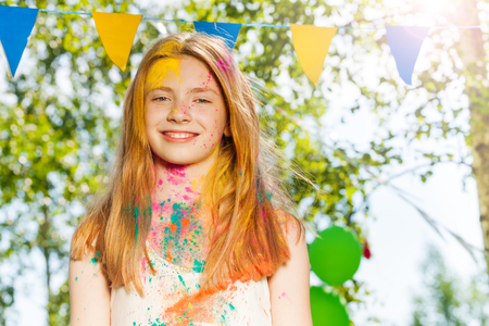 Portrait of happy young girl with face covered with colored powder on Holi color festivalの写真素材