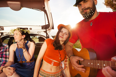 Close-up portrait of man playing guitar for his darling during a car trip in summerの写真素材