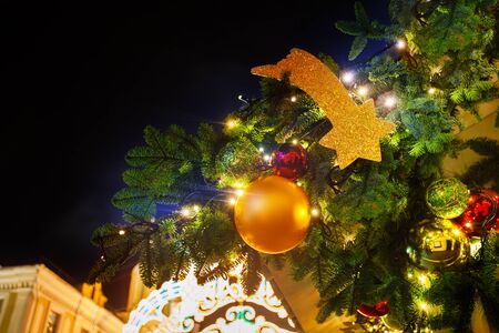 Bright festive city decor of fir branches, golden ornament balls, stars and light garlands on Christmas eveの写真素材