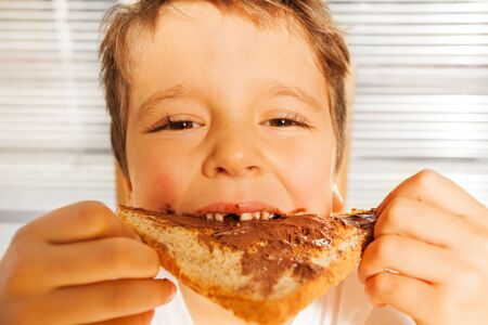 Happy kid boy eating toast with chocolate spreadの写真素材