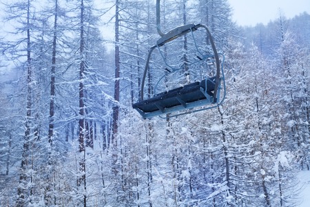 Empty chairlift against snow-covered forestの写真素材