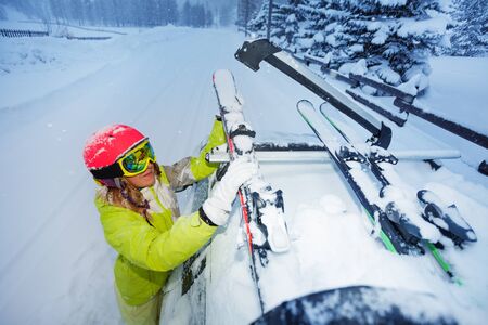 Female skier fastening skis to car roofs railsの写真素材