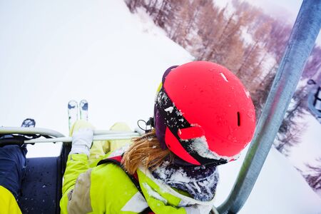 Female skier sitting at chairlift in high mountainの写真素材