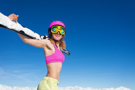 Sporty girl in helmet with skis against blue skyの写真素材