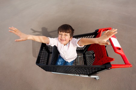 Cute boy having fun and playing with shopping cartの写真素材