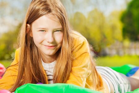 Beautiful girl laying on the lawn at sunny dayの写真素材