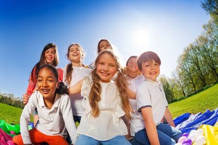 Happy kids sitting together on lawn at sunny dayの写真素材