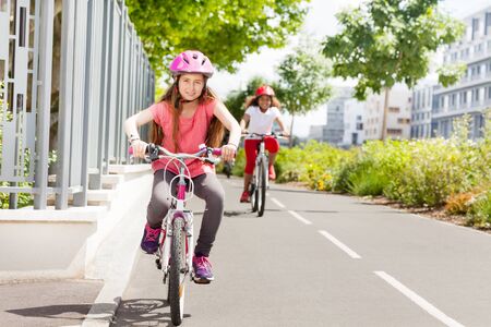 Girl riding bicycle catching up with her friendの写真素材