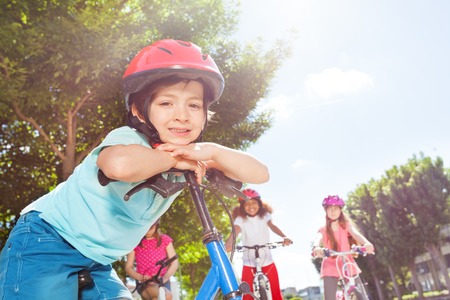 Smiling boy standing with bicycle at summer parkの写真素材