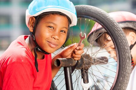 African boy repairing bicycle wheel with spannerの写真素材