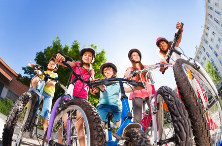 Happy little bike riders standing against blue skyの写真素材