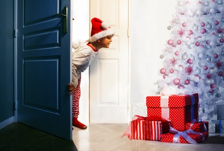 Boy checking presents under Christmas treeの写真素材