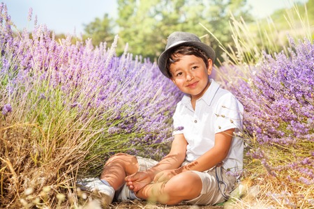 Little boy wearing hat, sitting in lavender fieldの写真素材