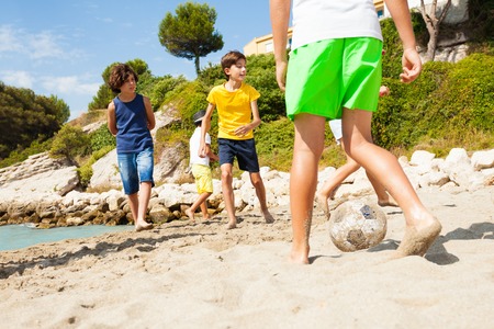 Kids playing football barefoot on sandy beachの写真素材