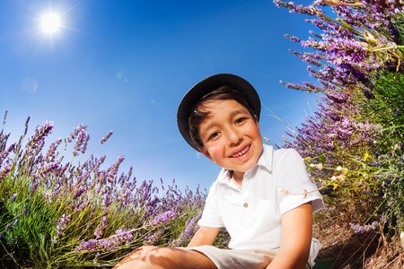 Smiling boy sits on the ground in lavender fieldの写真素材