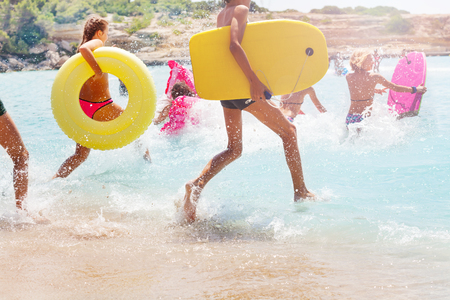 Group of kids running into sea to swimの写真素材