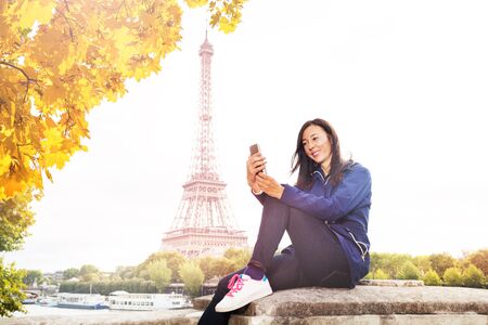 Woman texting on phone against the Eiffel Towerの写真素材