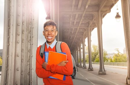African student with textbooks on city street