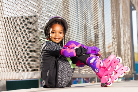 Cute girl in roller skates sitting at rollerdrom