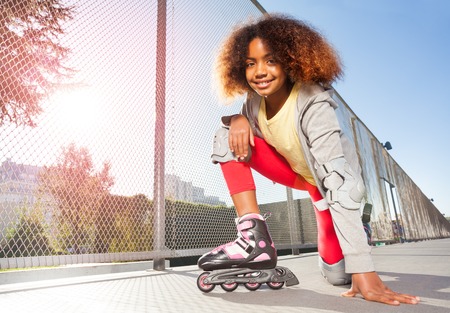 Happy African girl posing on floor at skate parkの写真素材