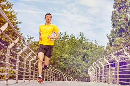 Young man running across the bridge at city park