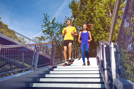 Sporty couple running downstairs on city stairsの写真素材