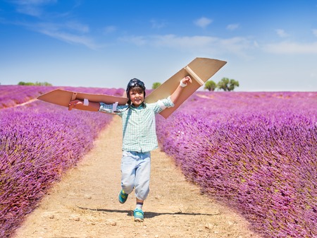 Happy boy waving cardboard wings trying to flyの写真素材