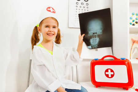 Girl in doctor costume playing dentist with x-rayの写真素材