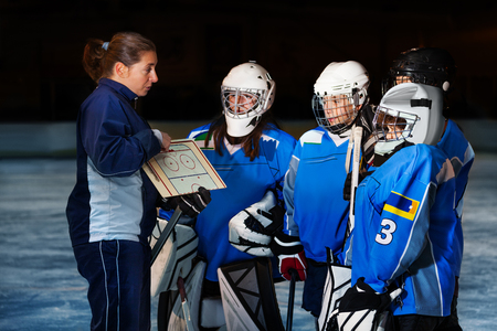 Female coach explaining game plan to hockey teamの写真素材