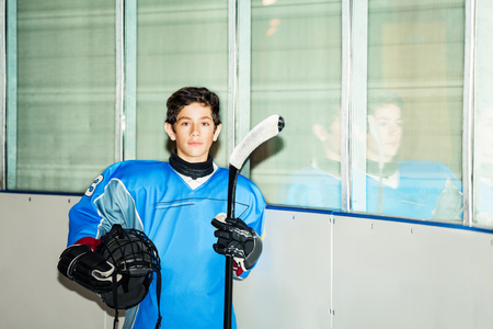 Young hockey player with helmet and stick at rinkの写真素材