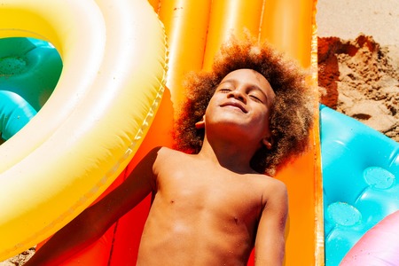 African boy enjoying summer laying on sandy beach