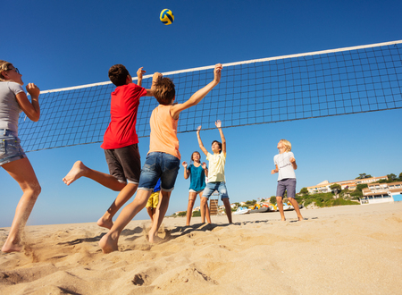 Boys and girls playing volleyball on the beachの写真素材