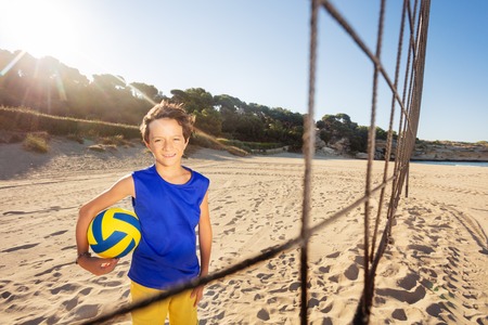 Happy volleyball player with ball on sand courtの写真素材