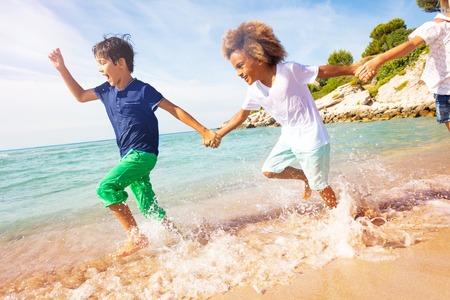 Happy boys running in shallow water on the beachの写真素材