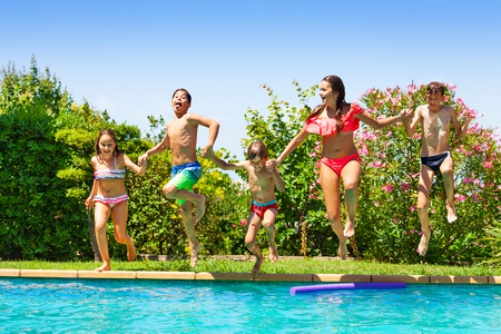Happy kids jumping into the swimming pool togetherの写真素材