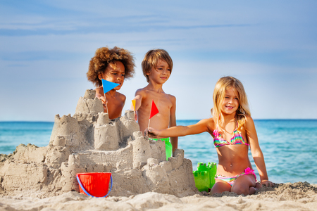 Happy friends making sandcastle on the beachの写真素材