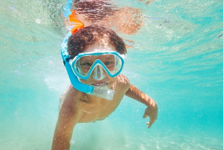 Happy kid boy snorkeling in clear blue sea