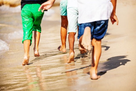 Kids running barefoot on sandy beach in summerの写真素材