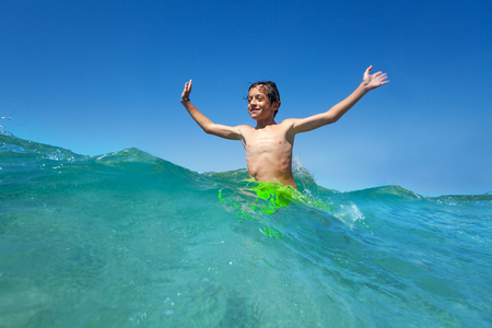 Happy teenage boy standing waist deep in sea waterの写真素材