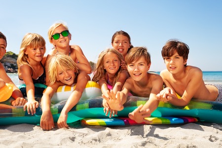 Happy friends sunbathing on sandy beach in summerの写真素材